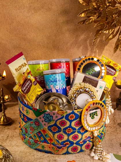 A unique fabric-covered hamper for Diwali, filled with treats and styled with traditional brass diyas to emphasize its handcrafted appeal.