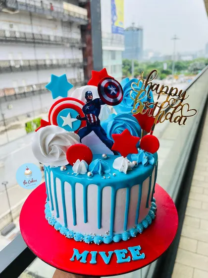 A heroic Captain America themed cake with a bold red, white, and blue design. This cake features a blue drip, buttercream swirls, and the iconic shield, perfect for a young superhero fan.