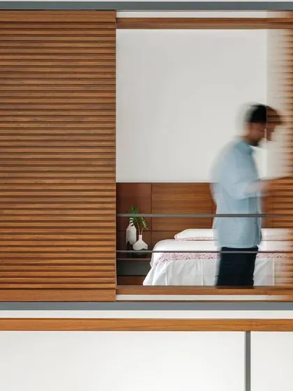 Sliding louvered screens in the Copper House create a flexible boundary between a bedroom and the central void. This allows the room to be either open to the rest of the house or enclosed for privacy, reflecting our interest in adaptable living spaces.