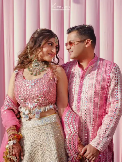 A lovely portrait of the couple against a pink backdrop at their Haldi ceremony. Their coordinated outfits and happy smiles say it all.