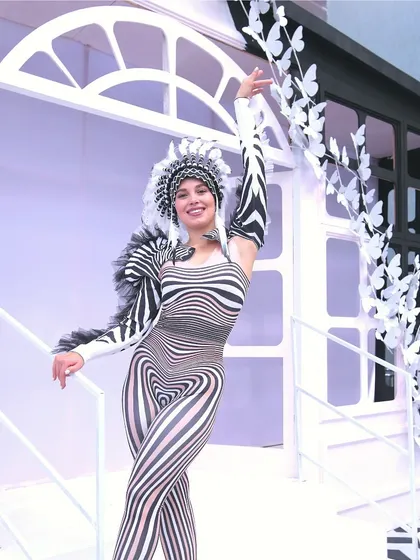A costumed performer poses against the clean, white architectural backdrop of our 'Line Art Carnival' theme.