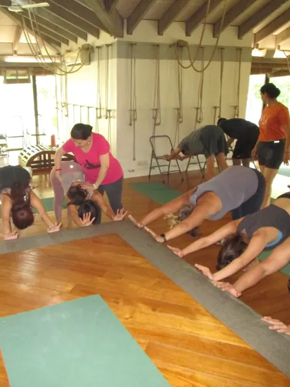 Students are practicing a supported forward bend, using the stage for support. This group setting allows for a shared experience of release and extension.