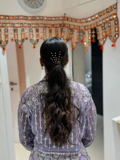 A chic and modern ponytail for the sister of the bride. The pearl hairpins add a touch of elegance to the simple, sleek style.