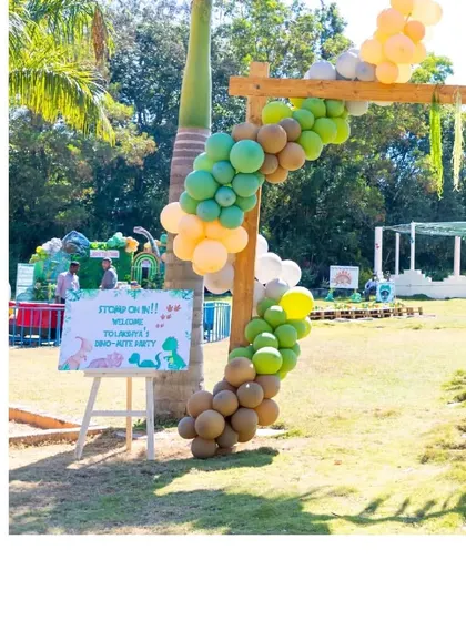 A welcome sign and balloon garland at the entrance of the dinosaur party.