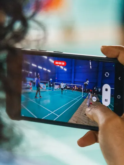 A spectator captures the on-court action on their phone. Our corporate tournaments generate excitement and engagement not just for the players, but for their colleagues as well.
