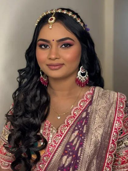 Mehendi magic in purple. This bride is glowing with soft glam makeup, voluminous hair, and a pop of purple on the eyes to match the floral hair accessories.
