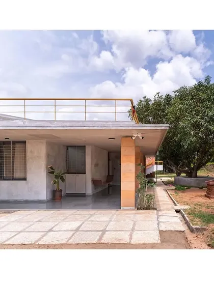 The simple, flat roofline of the "Aamra" house extends to create a generous carport and covered entrance. The use of CSEB pillars and a clean concrete slab maintains the project's honest and minimal material language.