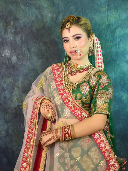 A full and clear look at the bride's attire, highlighting the contrast between the green outfit and the sheer pink dupatta.