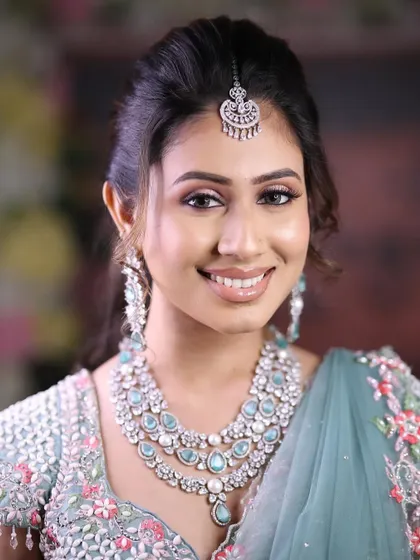 A close-up of the model smiling, wearing the pastel blue lehenga and a stunning multi-layered necklace.