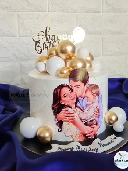 A heartwarming cake featuring an edible illustration of the family. This is a beautiful way to celebrate a husband and father, surrounded by gold and white spheres for an elegant touch.