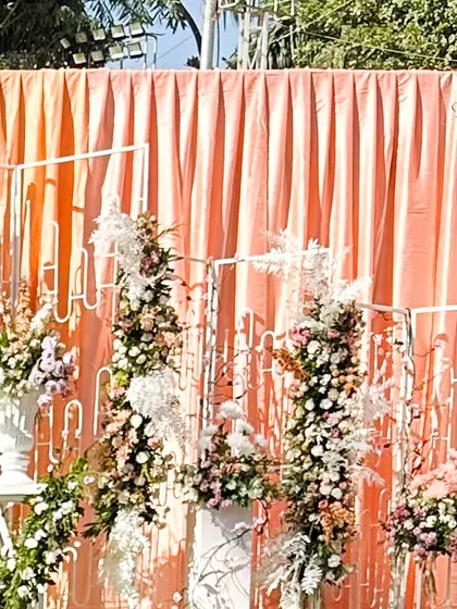 A closer look at the floral arrangements against peach drapes. The combination of different flowers and textures adds depth and beauty to the entrance decor.