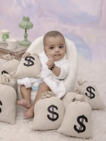 This little boss is ready to take on the world. A fun and creative "boss baby" theme with a bathrobe and bags of money shows off a playful and confident side.