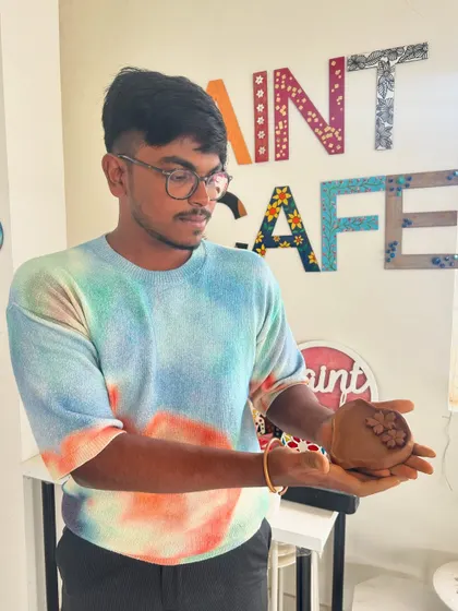 A participant proudly holding the small clay pot he created during a hand-building session.