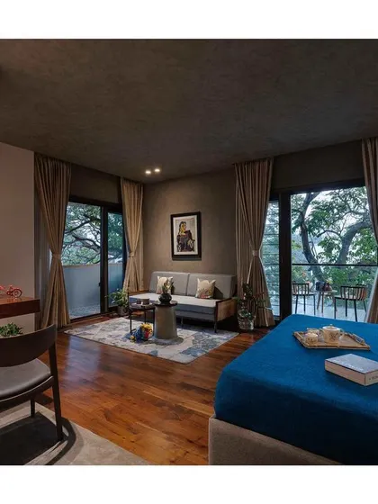This bedroom is designed as a suite, with a dedicated seating area and workspace. The large glass doors open to a balcony, offering an expansive view and plenty of natural light.