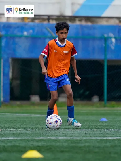 A young player focuses on ball control while navigating a cone drill. These fundamental exercises are crucial for developing the close control needed in modern football.