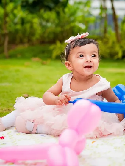 A beautiful outdoor portrait of a one-year-old girl enjoying her birthday picnic with balloon animals. We also offer milestone portrait sessions as part of the celebration.