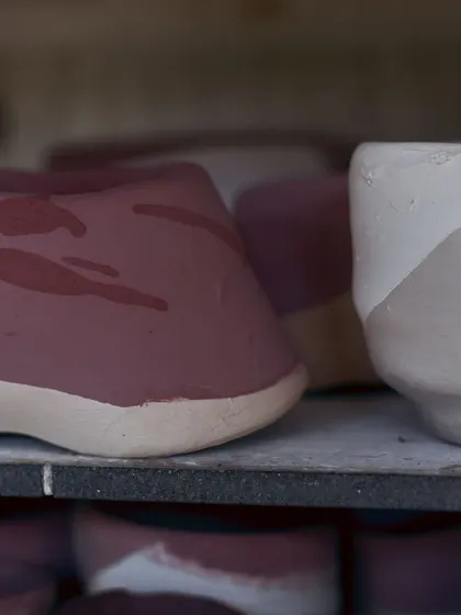 Pieces waiting on a kiln shelf, showing the beautiful, hand-painted patterns before they are transformed by the heat.