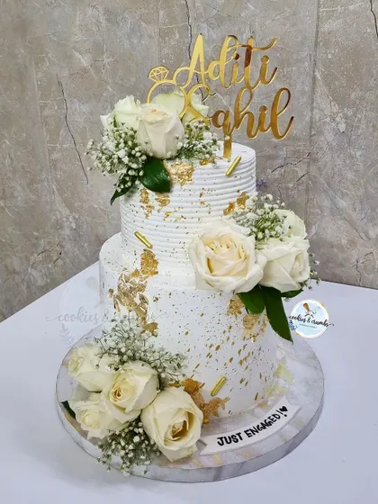 I love the drama of a lit-up tier. This three-tier engagement cake features a 'love' light, fresh white roses, and gold leaf accents, creating a stunning focal point for the celebration.