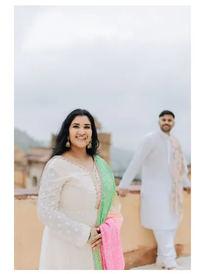 A bright and happy portrait of the bride, with the groom slightly out of focus in the background, creating a playful and modern feel.