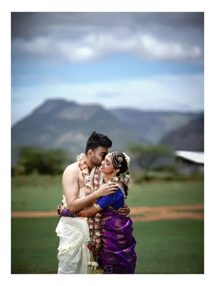 An intimate embrace during a post-wedding shoot, with the mountains creating a beautiful, layered background. The focus is on their connection, framed by the vastness of nature.