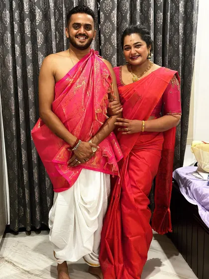 A full-length photo of the client couple in their coordinated pink and white traditional outfits.