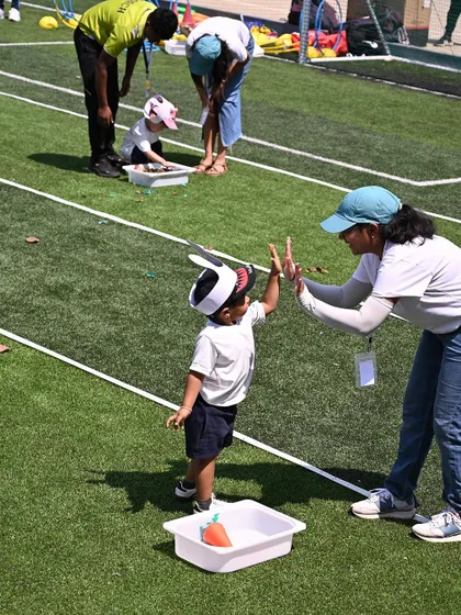 A high-five from an educator celebrates this toddler's successful completion of a task. Positive reinforcement is key to building confidence during physical challenges.