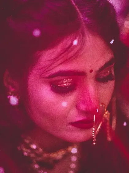 A close-up candid shot of the bride during the ceremony, capturing the emotion of the moment. The deep red tones and soft focus are part of my signature moody and artistic wedding photography style.