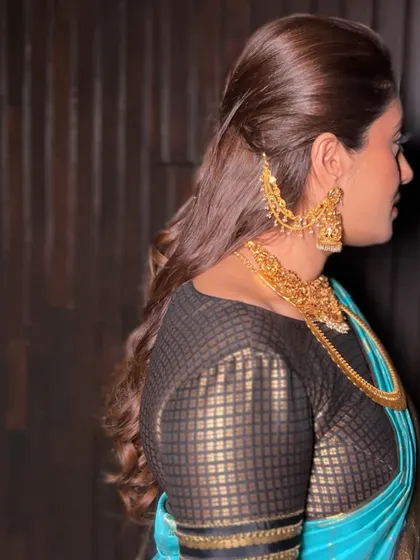 The soft waves of the hairstyle and the clean line of the saree pallu create a harmonious and polished look.