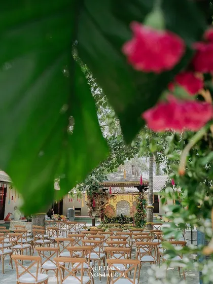 A creative shot of the Haldi seating area, viewed through the lush foliage of the entrance arch, adding depth and a sense of discovery.