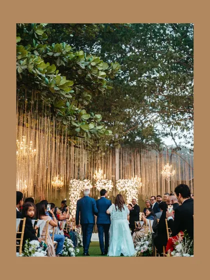A view from the back of the groom's procession down the aisle, showing the beautiful venue and the guests looking on.