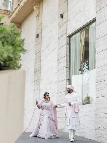 A stylish portrait of the couple walking together outside their modern wedding venue.