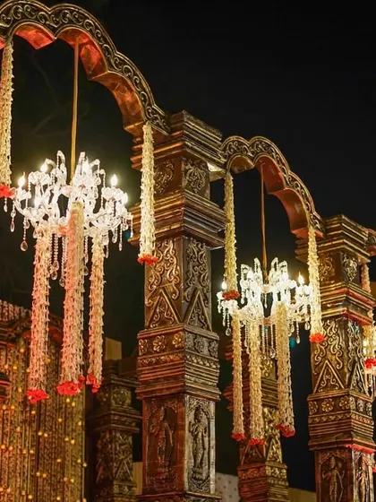 A close-up of the antique carved pillars, adorned with hanging floral chandeliers that combine traditional craftsmanship with elegant lighting.