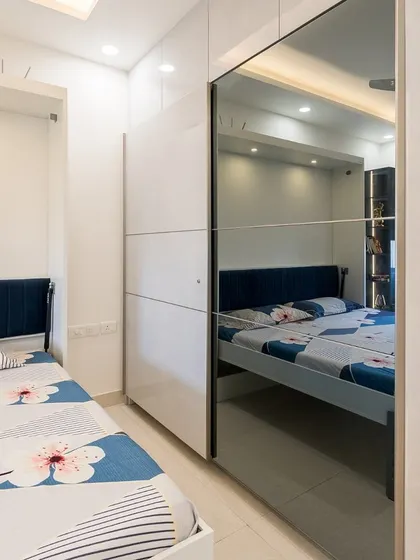 A bedroom featuring a white wardrobe with a full-length mirror on one of the sliding doors. This not only adds functionality but also helps to make the space feel brighter and more open.