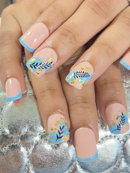A beautiful set of square-tipped extensions with a nude base. The design is elevated with light blue French tips and delicate, hand-painted foliage with gold foil accents.