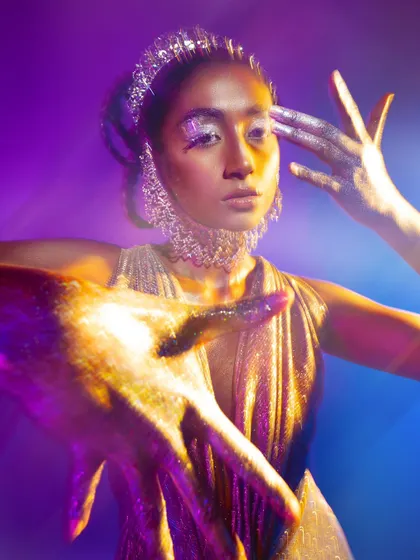 A dynamic pose from a creative beauty shoot, where light and glitter create a magical, otherworldly feel.