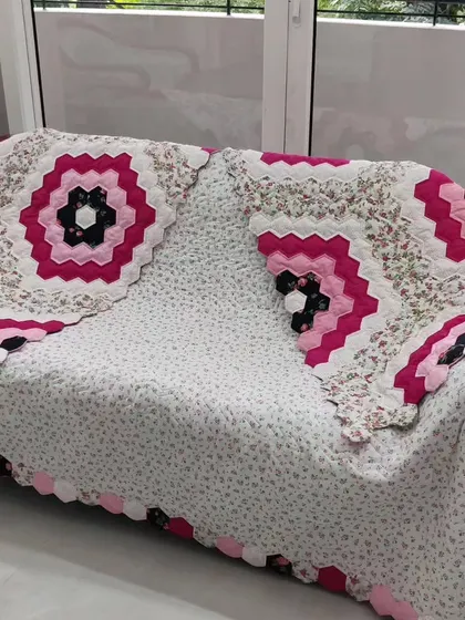 The "Grandmother's Flower Garden" quilt draped over a sofa, showing how it can be used as a beautiful home accent.