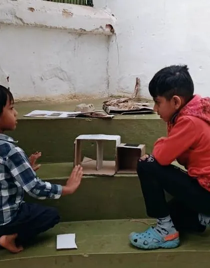 Two boys discuss their design for a mini insect hotel, collaborating and planning before they begin building.