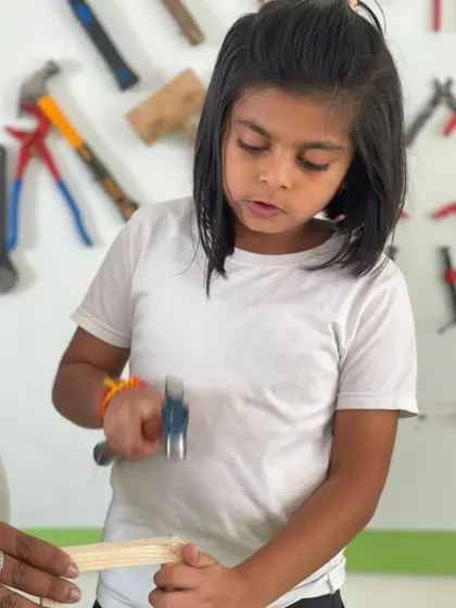 A young girl learns the proper way to hold a hammer and nail. Our instructors provide constant support to ensure safety and build confidence with every tap.