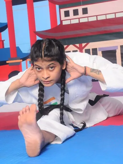 This image shows a student performing a deep stretch, which is essential for developing the flexibility required for advanced karate techniques and injury prevention.