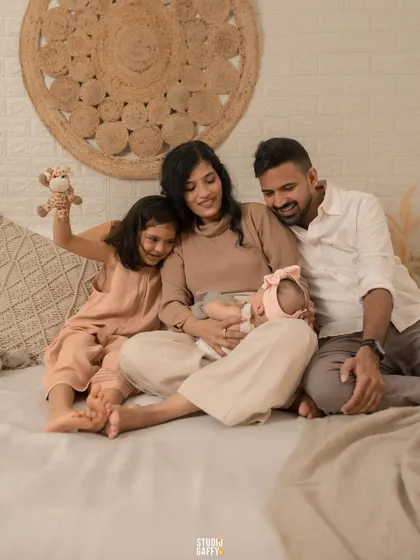 A heartwarming shot of a family of four admiring their newest member, the older sister playing gently with the baby.