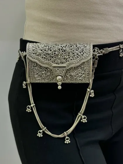 This is not just a bag, it's a wearable piece of art. Our exclusive silver purse is designed as a waist belt or fanny pack, featuring intricate carvings and dangling ghungroos for a bohemian-chic look.