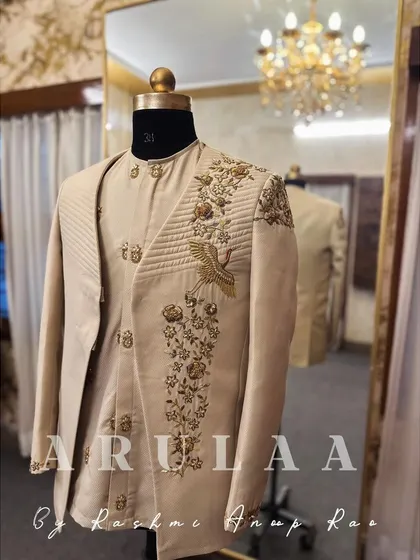 This Indo-Western suit in a beige fabric features beautiful quilted panels and intricate gold embroidery. The highlight is the elegant crane motif, a symbol of grace, which we embroidered using detailed zardosi work.
