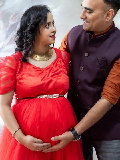 A loving couple's portrait in the studio, with the dad-to-be gently holding the baby bump.