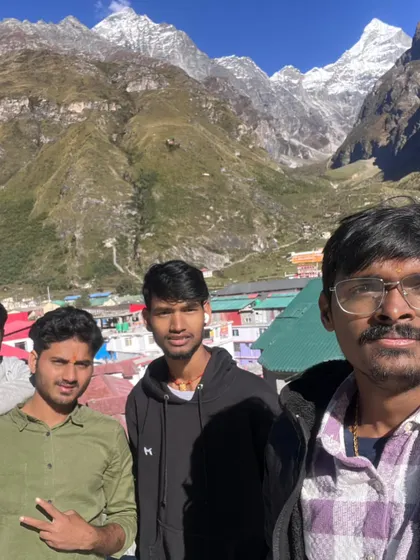 A group of friends taking a selfie at Badrinath, with the Neelkanth peak in the background. Our Do Dham and Char Dham packages ensure you experience the divinity of every holy site.