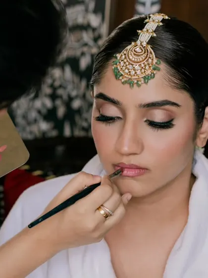 The bride getting her final touches, with her maang tikka being placed. A classic getting-ready shot.