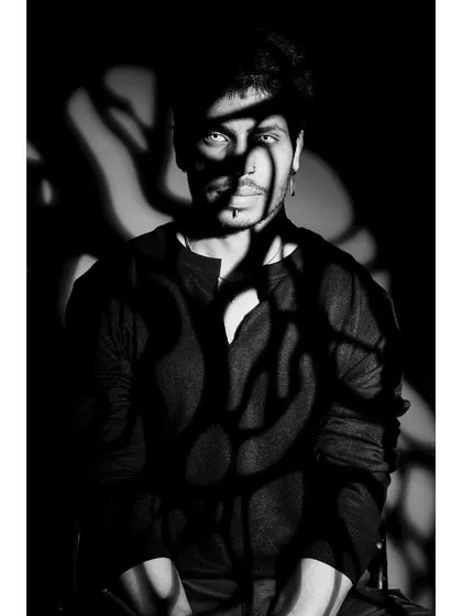 An artistic, black and white portrait using projected shadows to create a dramatic pattern on the model's face and torso. This experimental lighting is great for creating unique, conceptual fashion images.