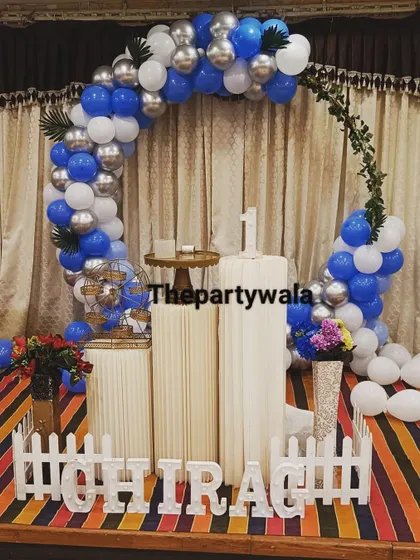 A blue, white, and silver balloon ring with a 'Happy Birthday' sign.