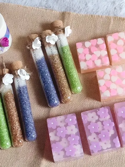 A beautiful flat lay of some of my handmade products available for custom hampers, including heart and flower-themed soaps, bath salts in test tubes, and a pillar candle.