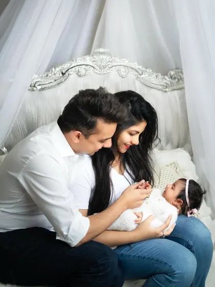 A fairy-tale setting for a new family. The elegant headboard and canopy create a dreamy backdrop for this intimate family portrait.
