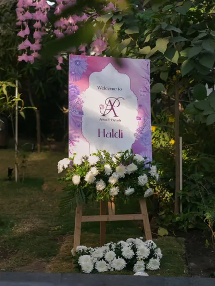 A personalized welcome sign for the Haldi ceremony, adorned with fresh white chrysanthemums. This is the first touchpoint for guests, and I ensure it reflects the event's elegant and personal nature.